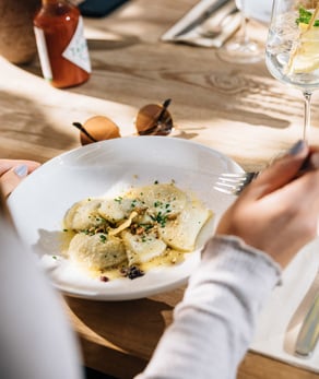 Giovane donna che si gode i tradizionali Schlutzkrapfen tirolesi