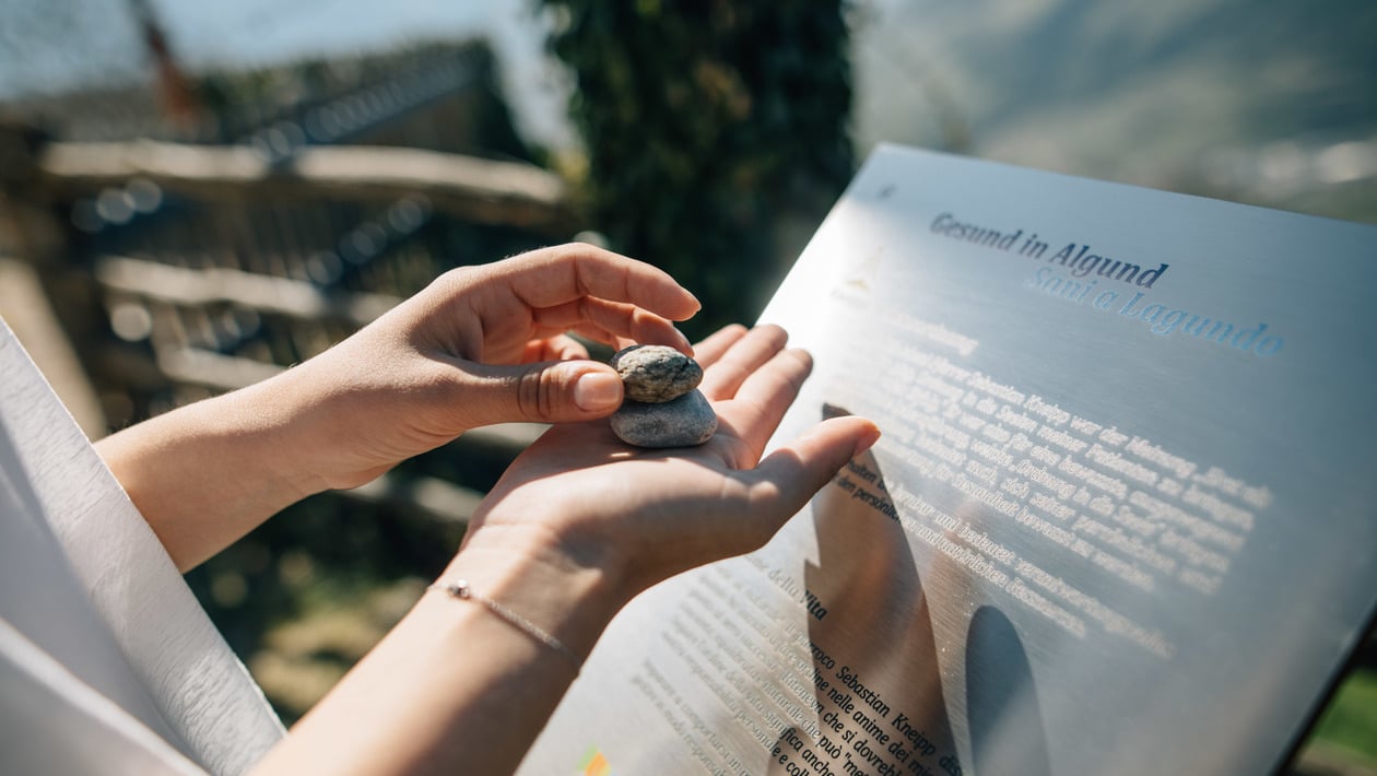 Woman feels stones in front of a "Healthy in Algund" sign